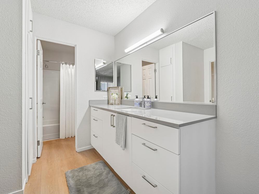 Renovated Package I bath with white cabinetry, grey quartz countertops, and hard surface flooring