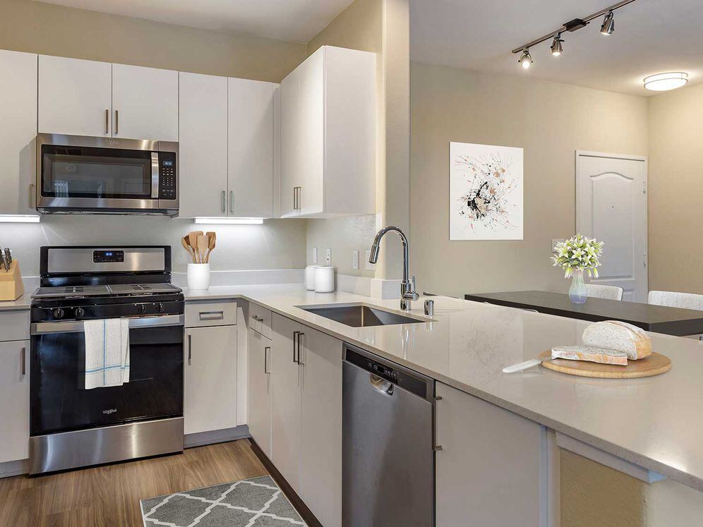 Renovated Package I kitchens with light grey quartz countertops, new white cabinetry, stainless steel appliances, upgraded fixtures, and hard surface flooring throughout