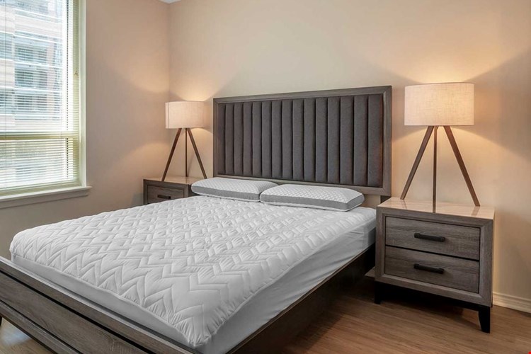 Furnished+ apartment homes feature queen bed with mattress, two pillows, dresser, nightstands, lamp, and mirror. (Representative Image – exact items and style of furnishings may vary)