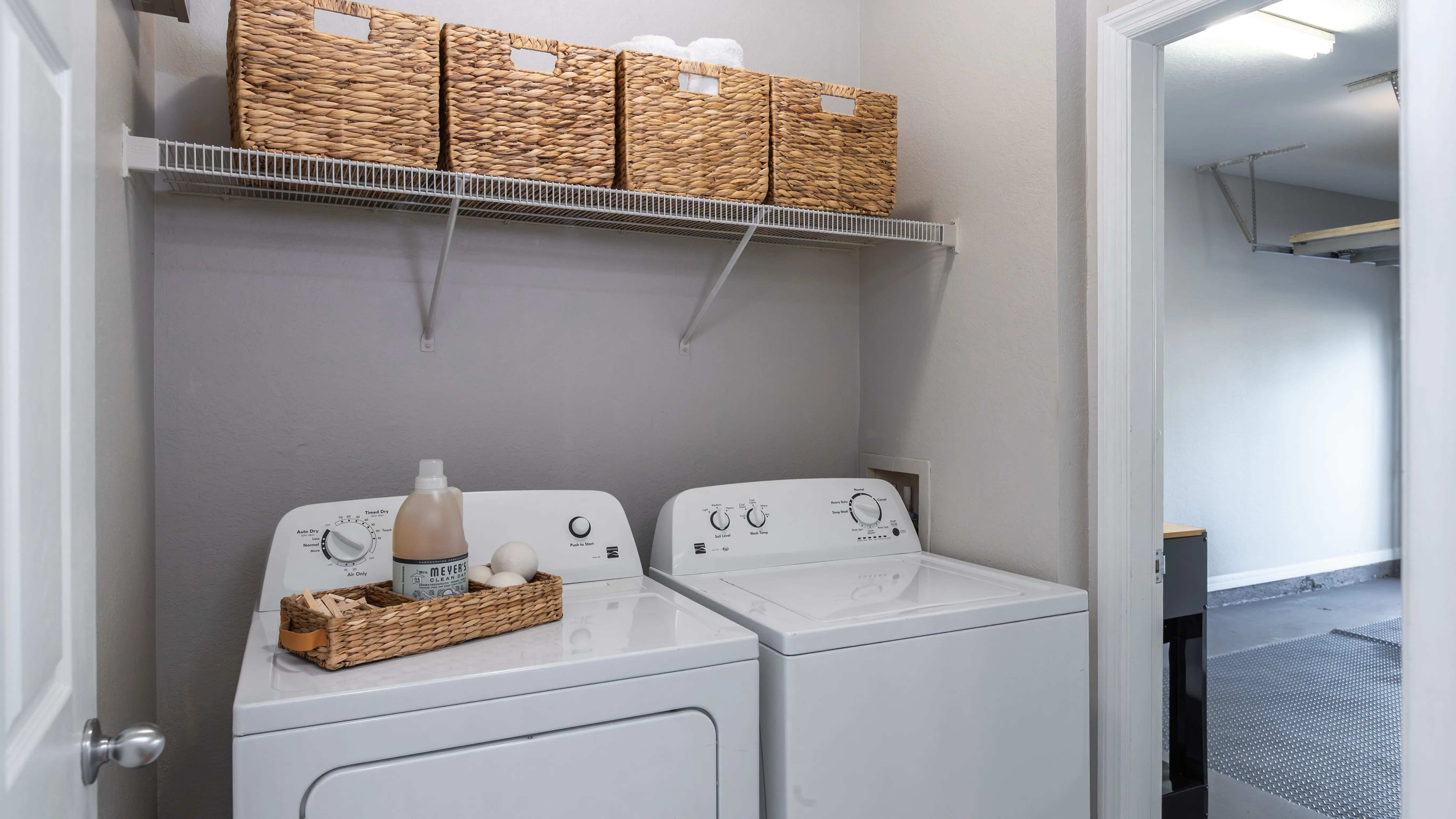 A dedicated laundry space featuring full-sized appliances and built-in shelving for added storage and efficiency.