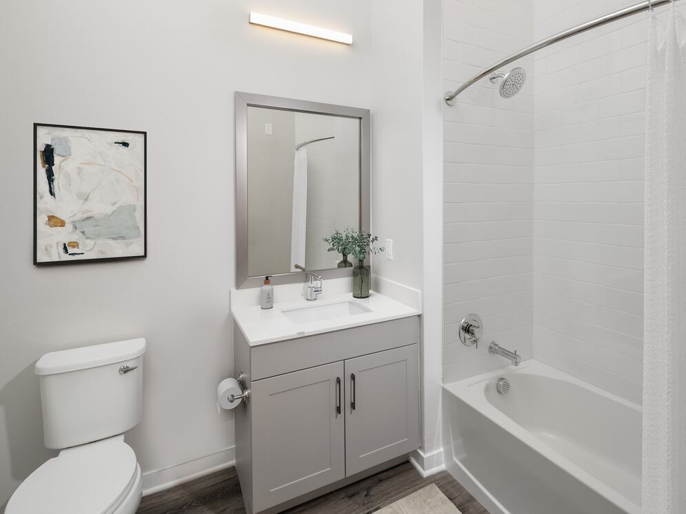 Upgrade Collection II bath with white quartz countertop, grey cabinetry, and hard-surface flooring