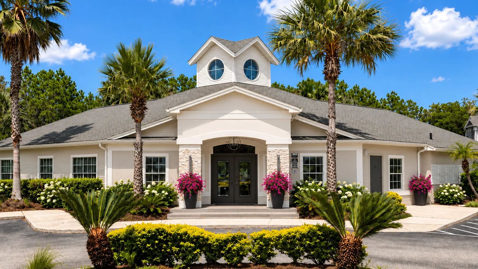 The leasing office at Indigo Isles offers a welcoming first impression, surrounded by lush palm trees, vibrant flowers, and beautifully maintained landscaping that reflects the community’s inviting atmosphere.