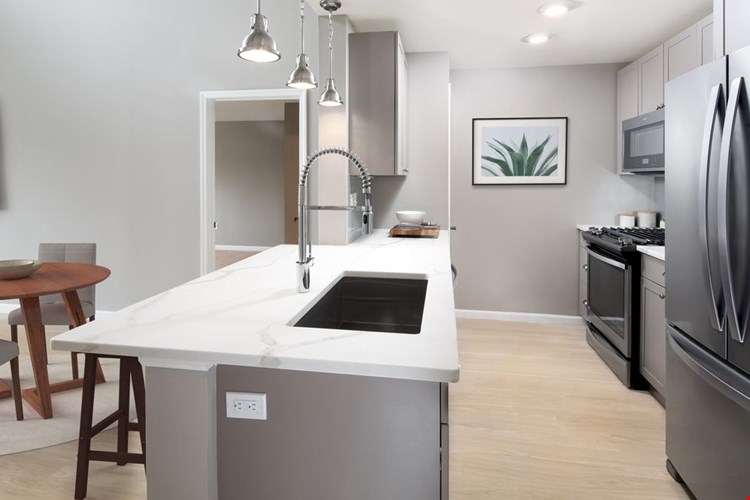 Premier Finish kitchen with grey cabinetry, white quartz countertops, stainless steel appliances, and hard surface flooring