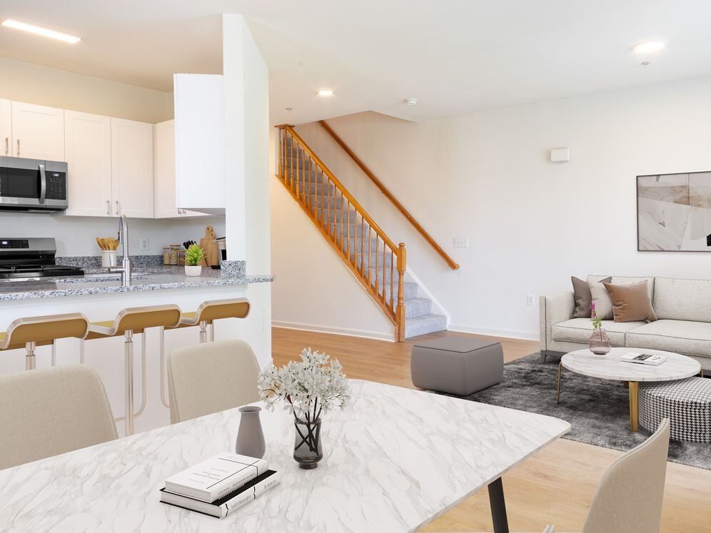 Renovated Package I kitchen, living, and dining areas with white cabinetry, grey granite countertops, stainless steel appliances, and hard surface plank flooring