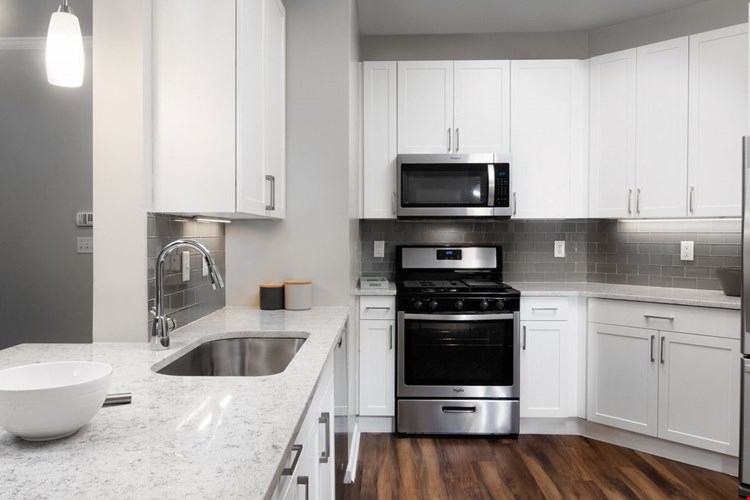 Classic Finish kitchen with white cabinetry, white quartz countertops, tile backsplash, stainless steel appliances, and hard surface flooring