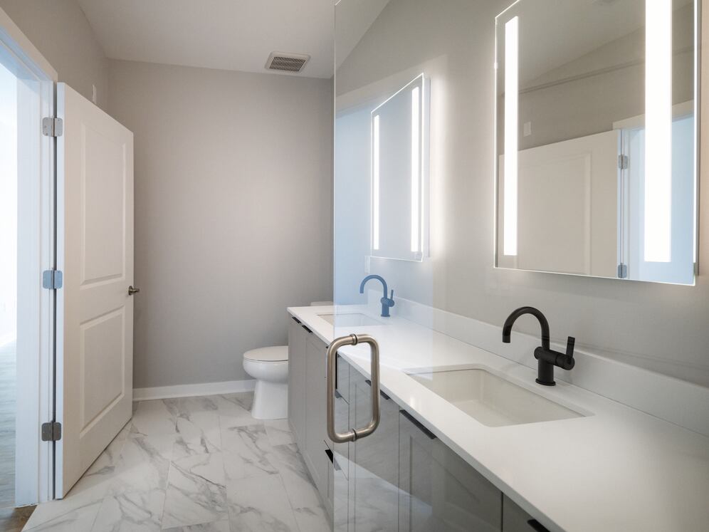 Signature Collection Primary bath with dual vanity sinks, grey shaker cabinetry, and white quartz countertops