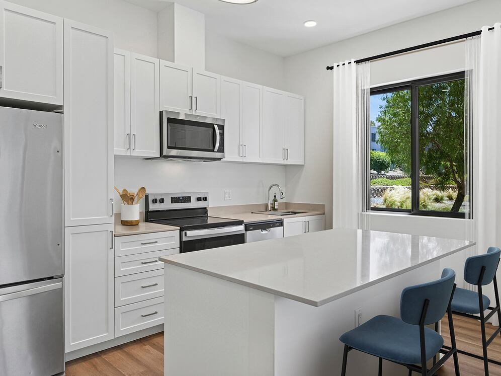 Freestanding Home kitchen with stainless steel appliances, white cabinetry, beige quartz countertops, and hard-surface flooring