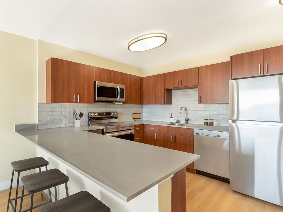 Kitchen with espresso cabinetry, grey quartz countertops, grey subway tile backsplash, stainless steel appliances, and hard surface flooring
