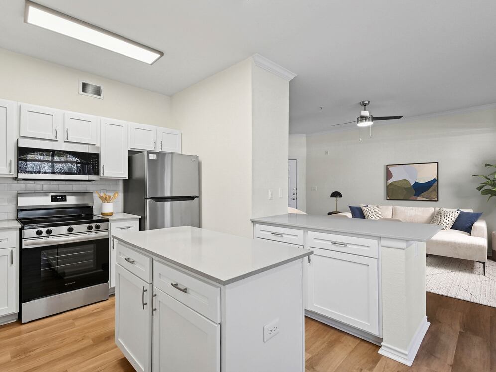Renovated Package I kitchen with stainless steel appliances, white cabinetry, white tile backsplash, grey quartz countertops, and hard surface flooring