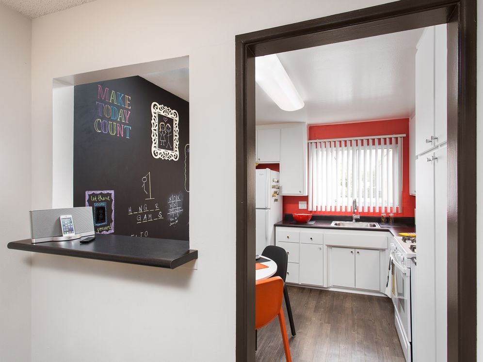 Classic Package II kitchen with white or black appliances, black laminate countertops, white cabinetry, and hard surface flooring (select homes)