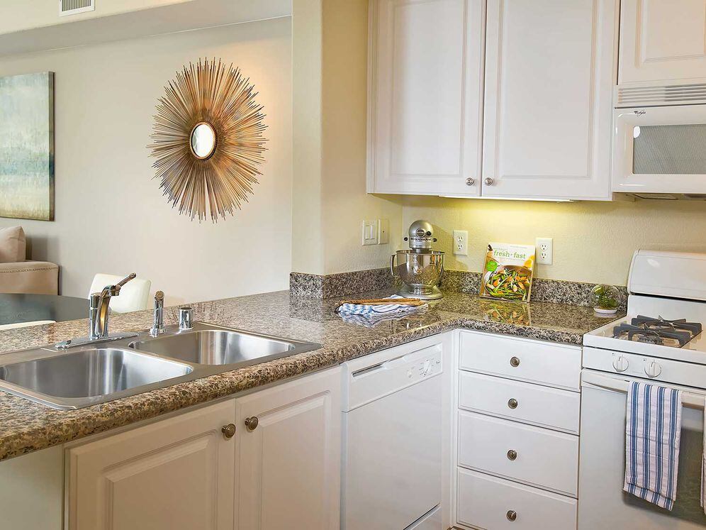 Classic Package I kitchen with white appliances, beige speckled granite countertop, white cabinetry, and hard surface flooring