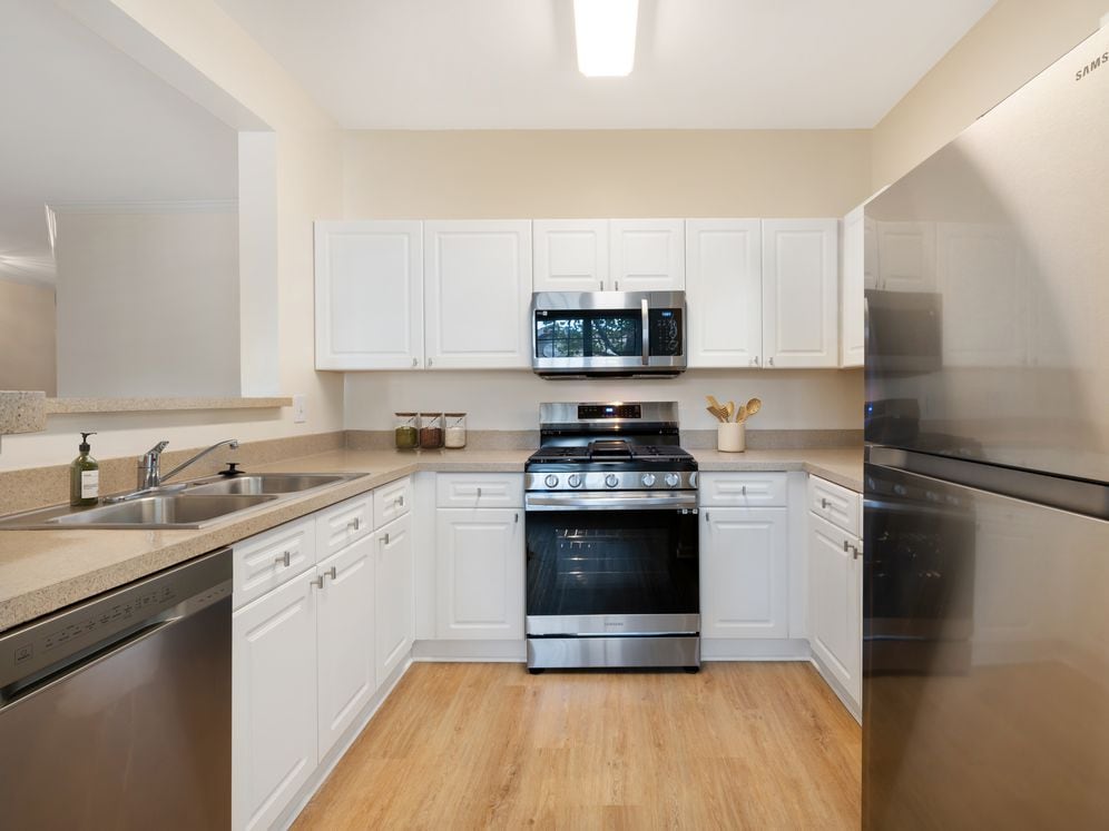Classic Package II kitchen with white cabinetry, beige laminate countertops, stainless steel appliances, and hard surface flooring
