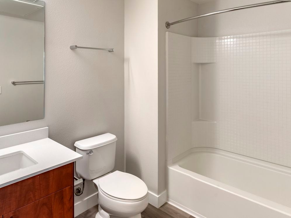 Renovated Package I bath with white quartz countertop, cherry cabinetry, and hard surface flooring