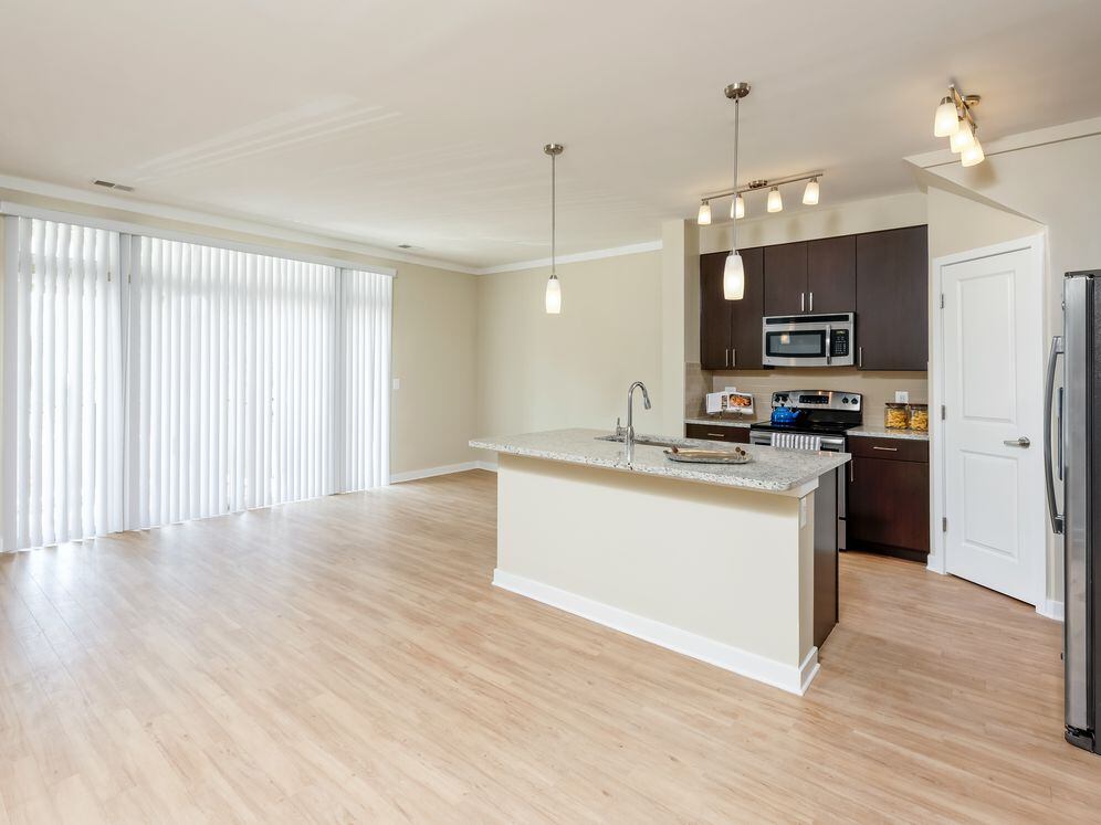 Living area and open concept kitchen with granite countertop, espresso cabinetry, stainless-steel appliances, kitchen island and hard surface flooring
