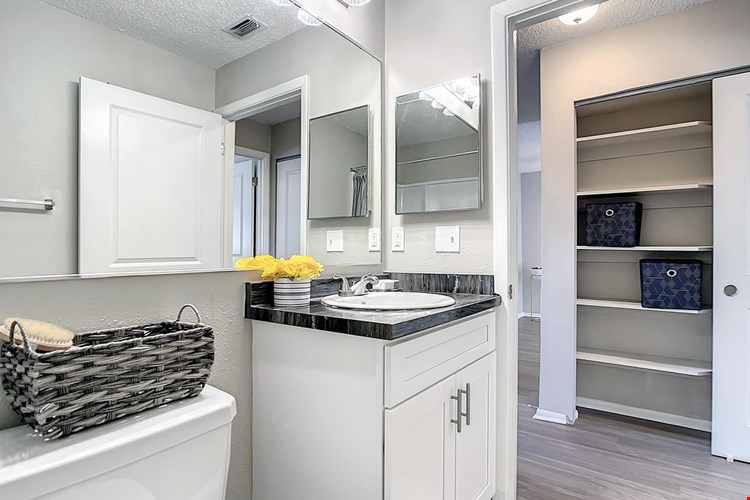 Bathrooms featuring wood-style flooring, black-fusion countertops, and large mirrors.