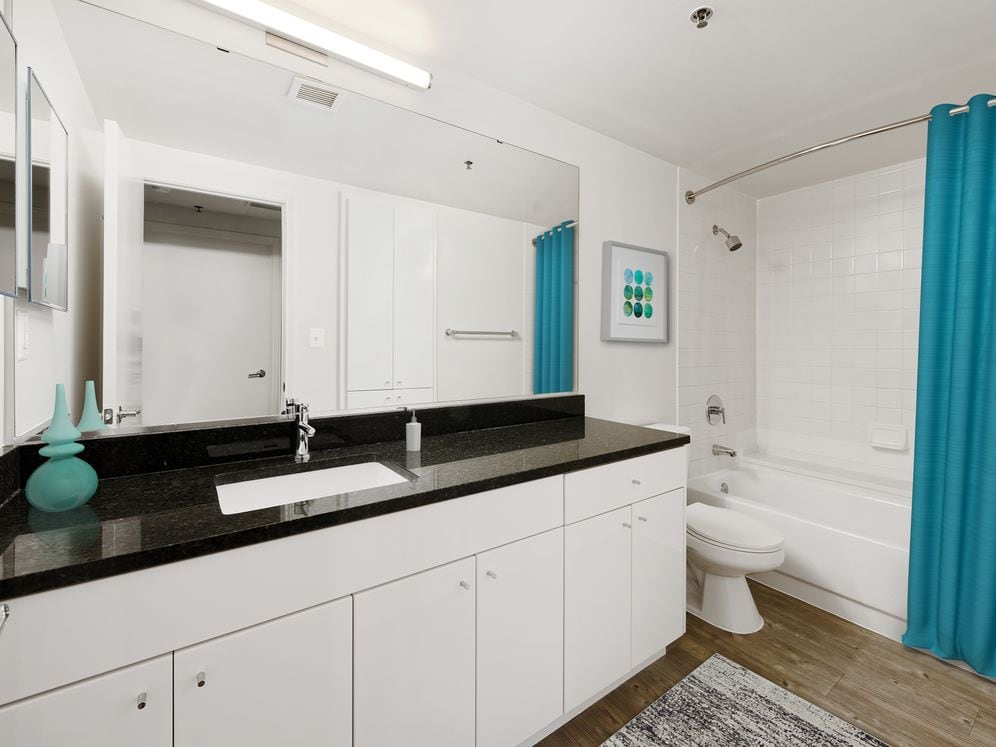 Renovated Package I bath with black granite countertop, white cabinetry, and hard surface flooring