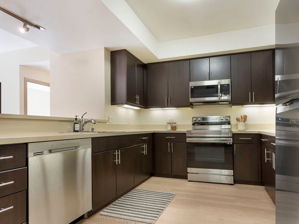 Classic Collection II kitchen with stainless steel appliances, beige quartz countertops, espresso cabinetry, and hard surface flooring