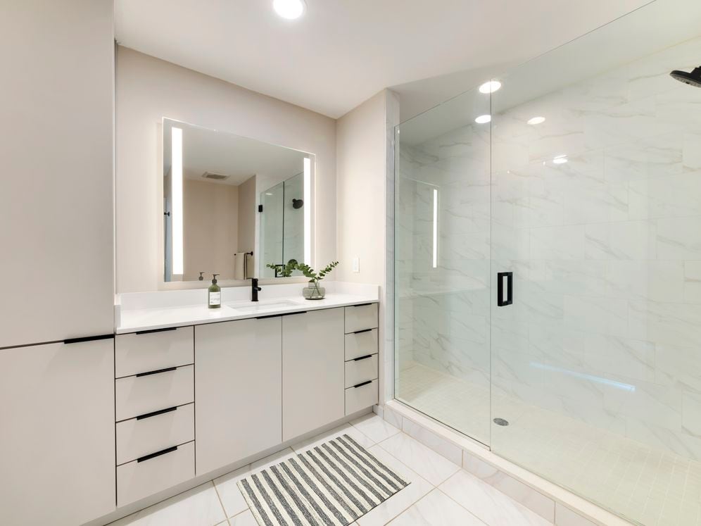 Tower Building - Renovated bath with white quartz countertop, light grey cabinetry, and tile flooring
