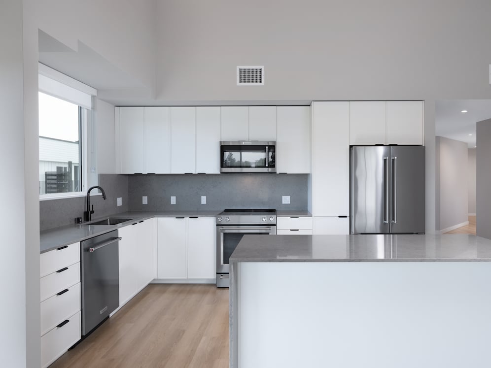 Signature Collection II Apartment with kitchen featuring white cabinetry, grey quartz backsplash and countertop, upgraded stainless steel appliances, and more