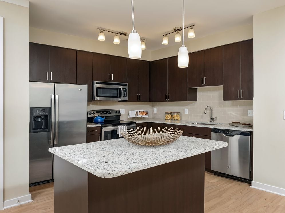 Open concept kitchen with espresso cabinetry, granite countertops, kitchen island, stainless-steel appliances and hard surface flooring