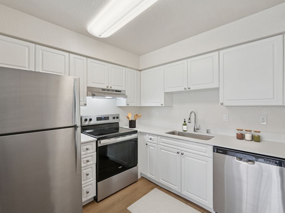 Classic II Collection kitchen with stainless steel appliances, white cabinetry, quartz countertops, and hard surface flooring