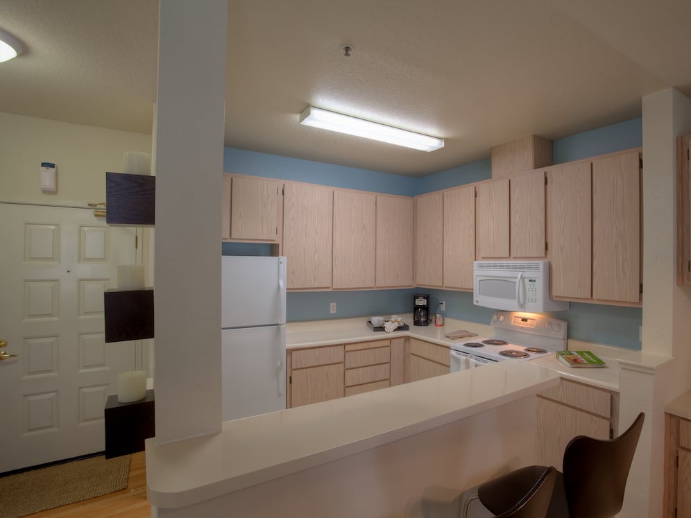 Classic Package I kitchen with light oak cabinetry, white laminate countertops, white appliances, and hard surface flooring