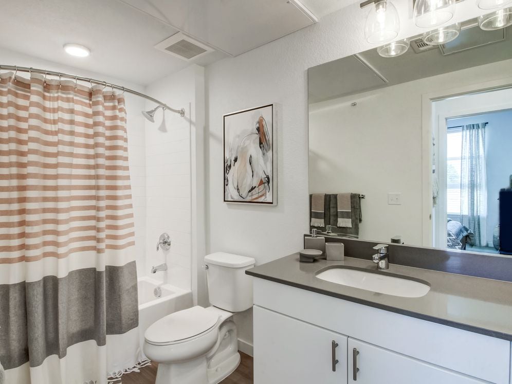 Bathrooms with white cabinetry, grey quartz countertops, and luxury vinyl plank flooring