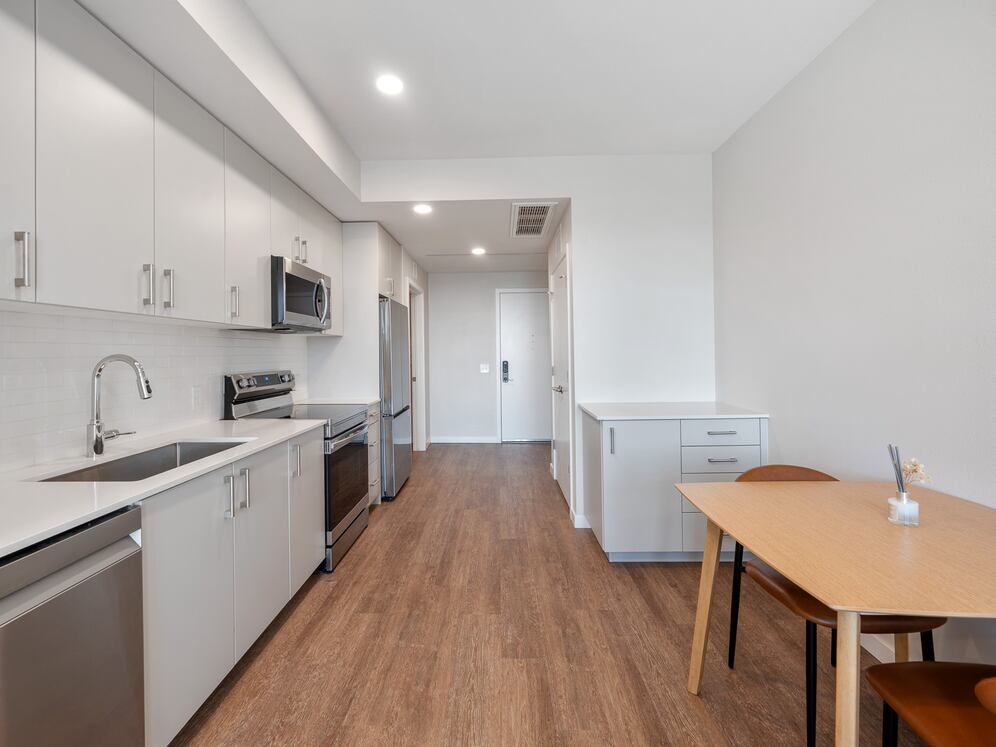 Finish Scheme II kitchen with light cabinetry, eggshell quartz countertops, white tile backsplash and stainless steel appliances.