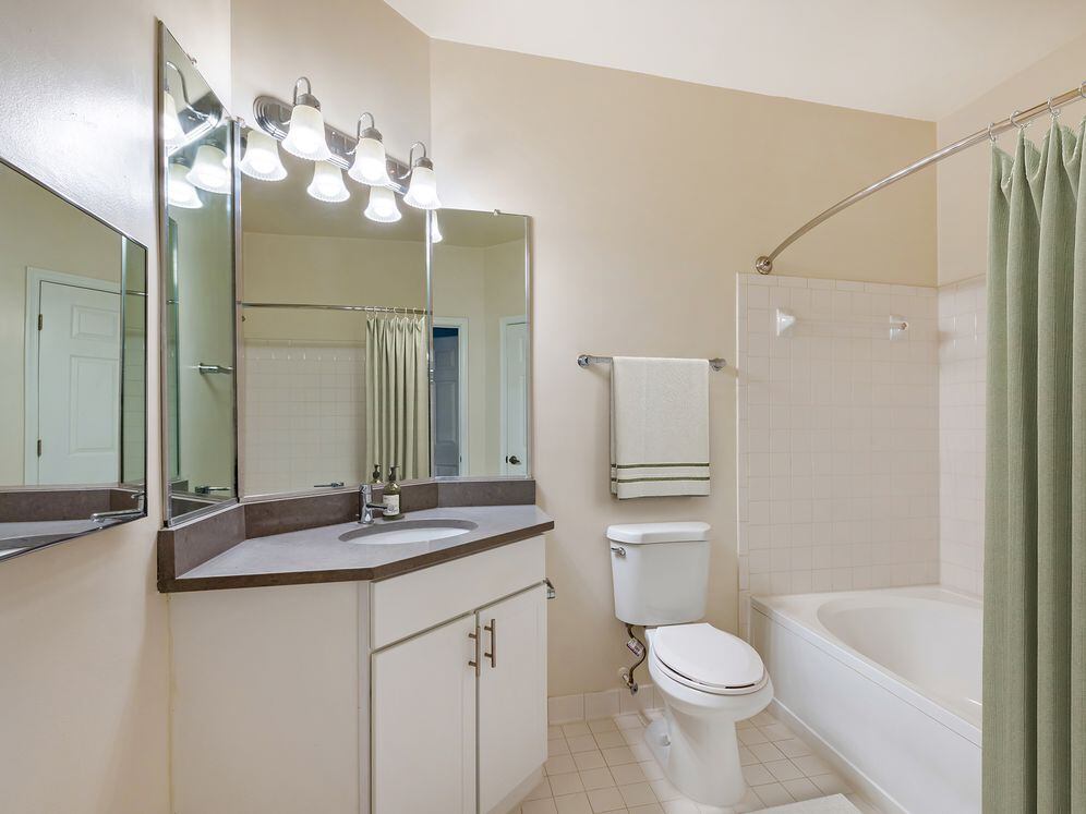 Renovated Package I bath with white cabinetry, grey quartz countertops, and hard surface flooring