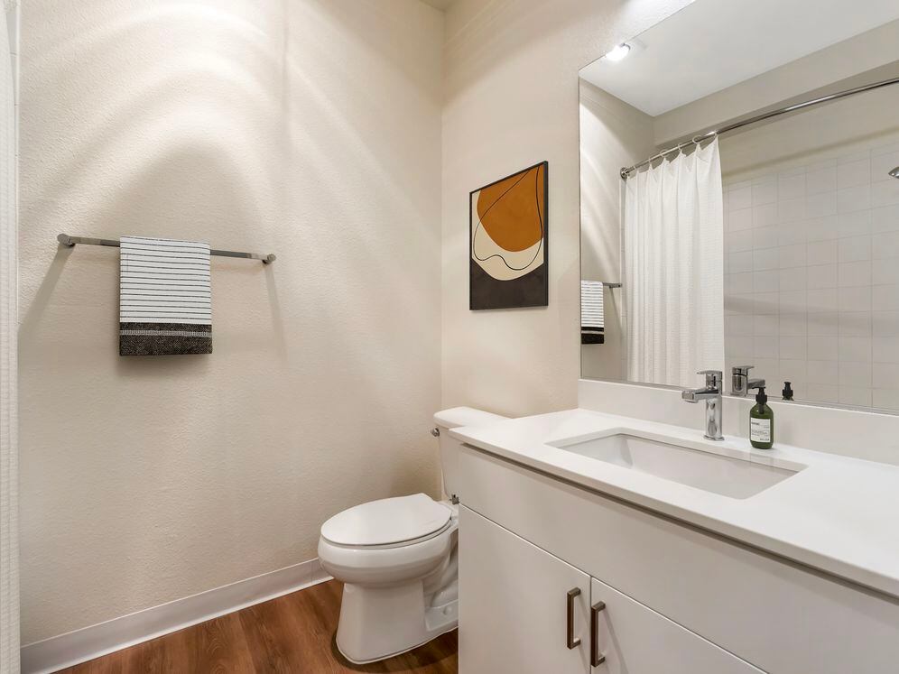 Renovated Package I bath with white quartz countertop, white cabinetry, and hard surface flooring