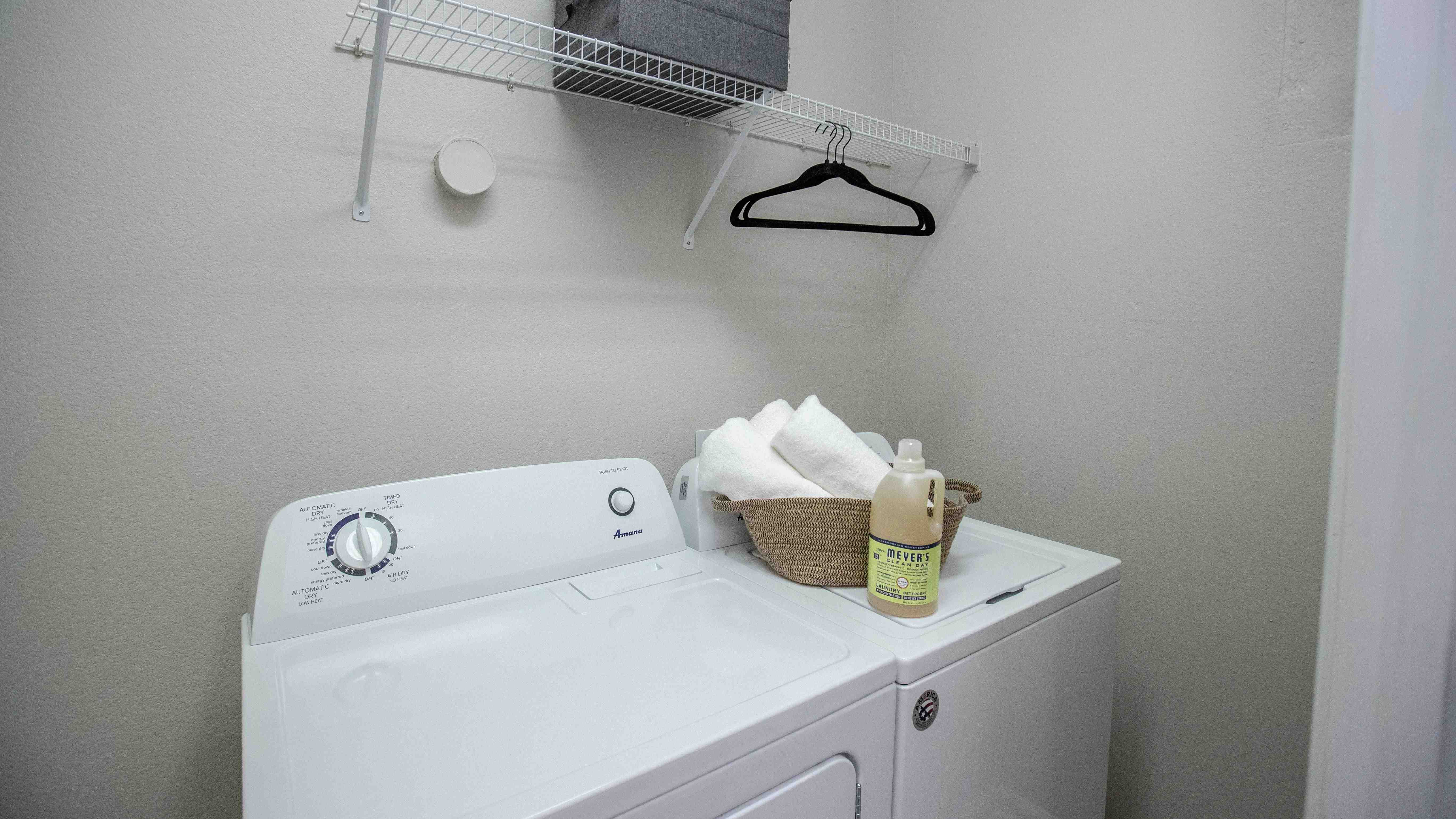Enjoy the ease of in-home laundry with a full-size washer and dryer set, complete with additional overhead shelving for organized storage. 