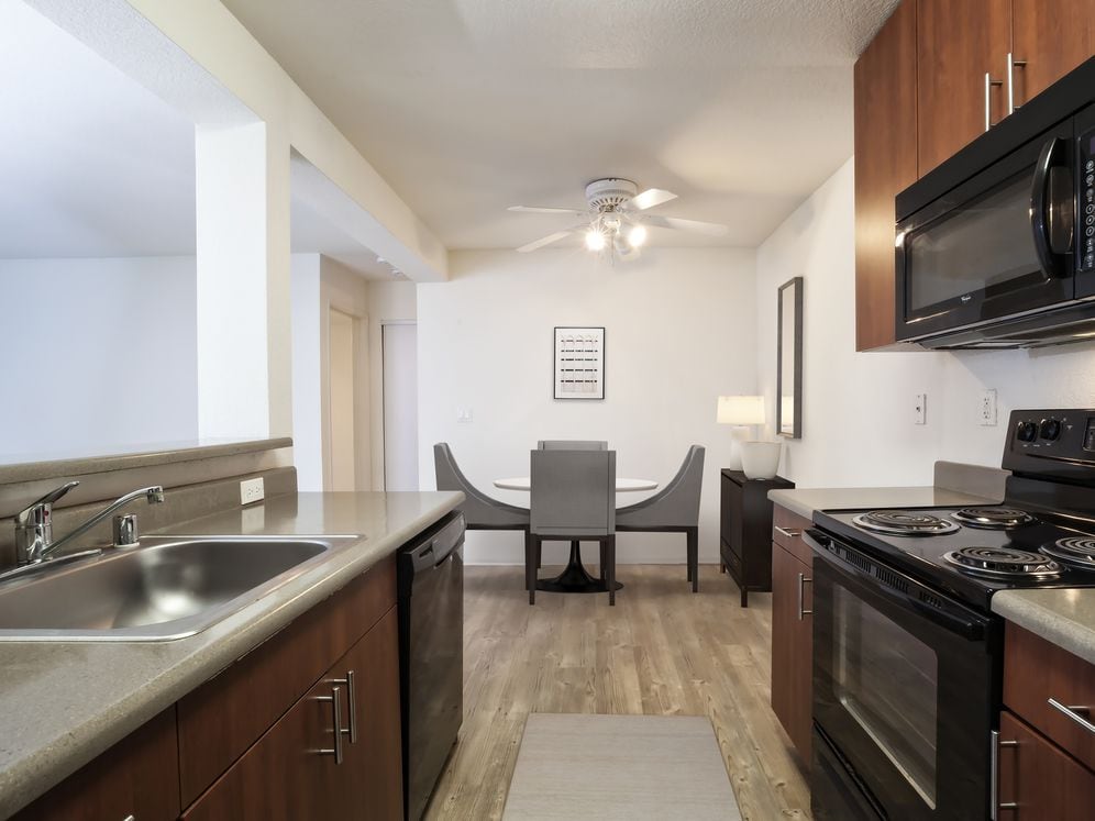 Kitchen with light countertops, cherry cabinetry, black appliances and hard surface flooring