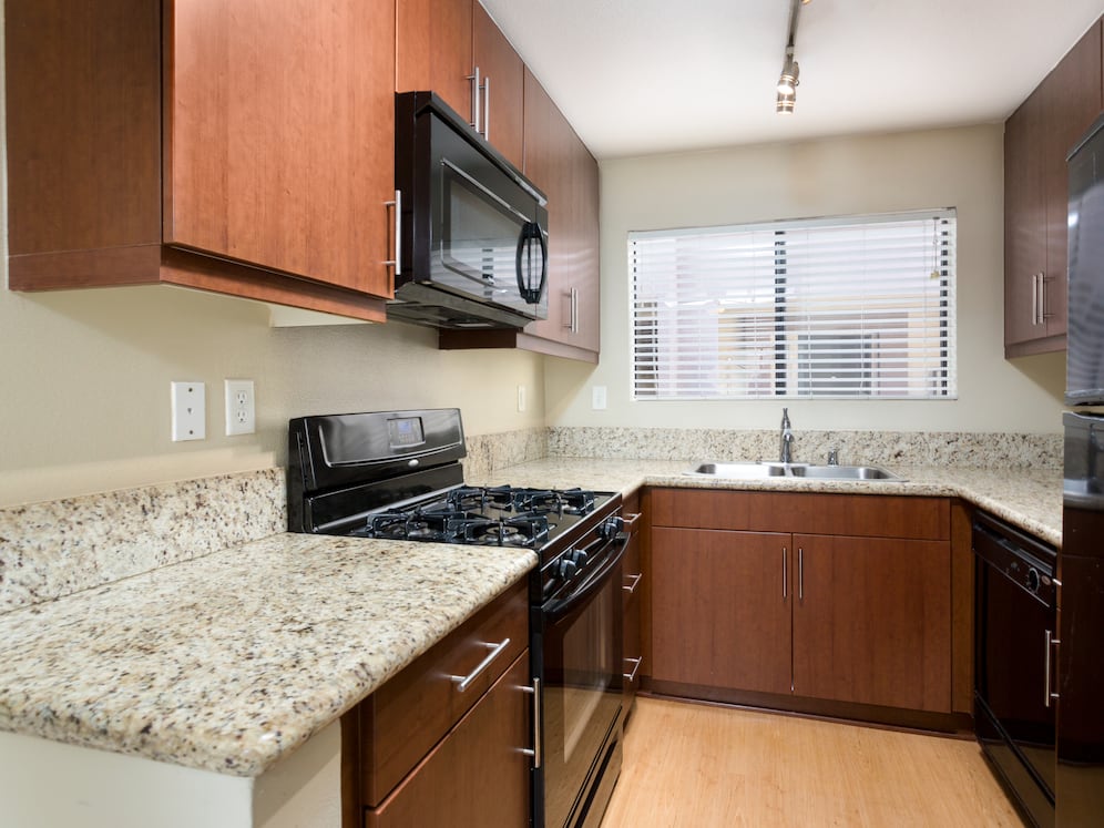 Classic Package I kitchen with chestnut cabinetry, beige speckled granite countertops, black appliances, and hard surface flooring