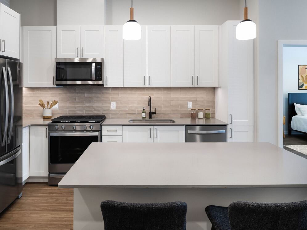 Upgrade Collection Kitchen with white shaker cabinetry, grey quartz countertops, beige tile backsplash, and stainless steel appliances