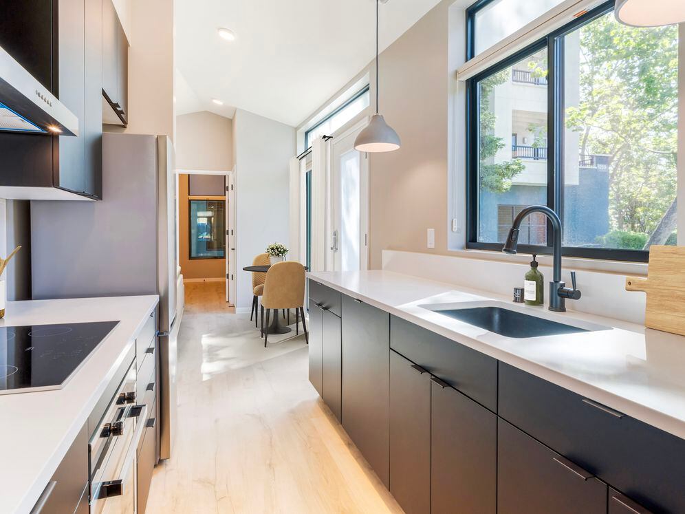 Freestanding home kitchen with stainless steel appliances, white quartz countertops, black cabinetry, and hard surface flooring