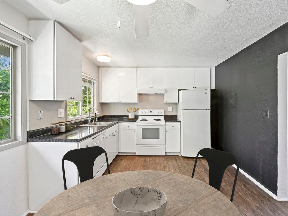 Kitchen with white cabinetry, black laminate countertops, white appliances, and hard surface flooring