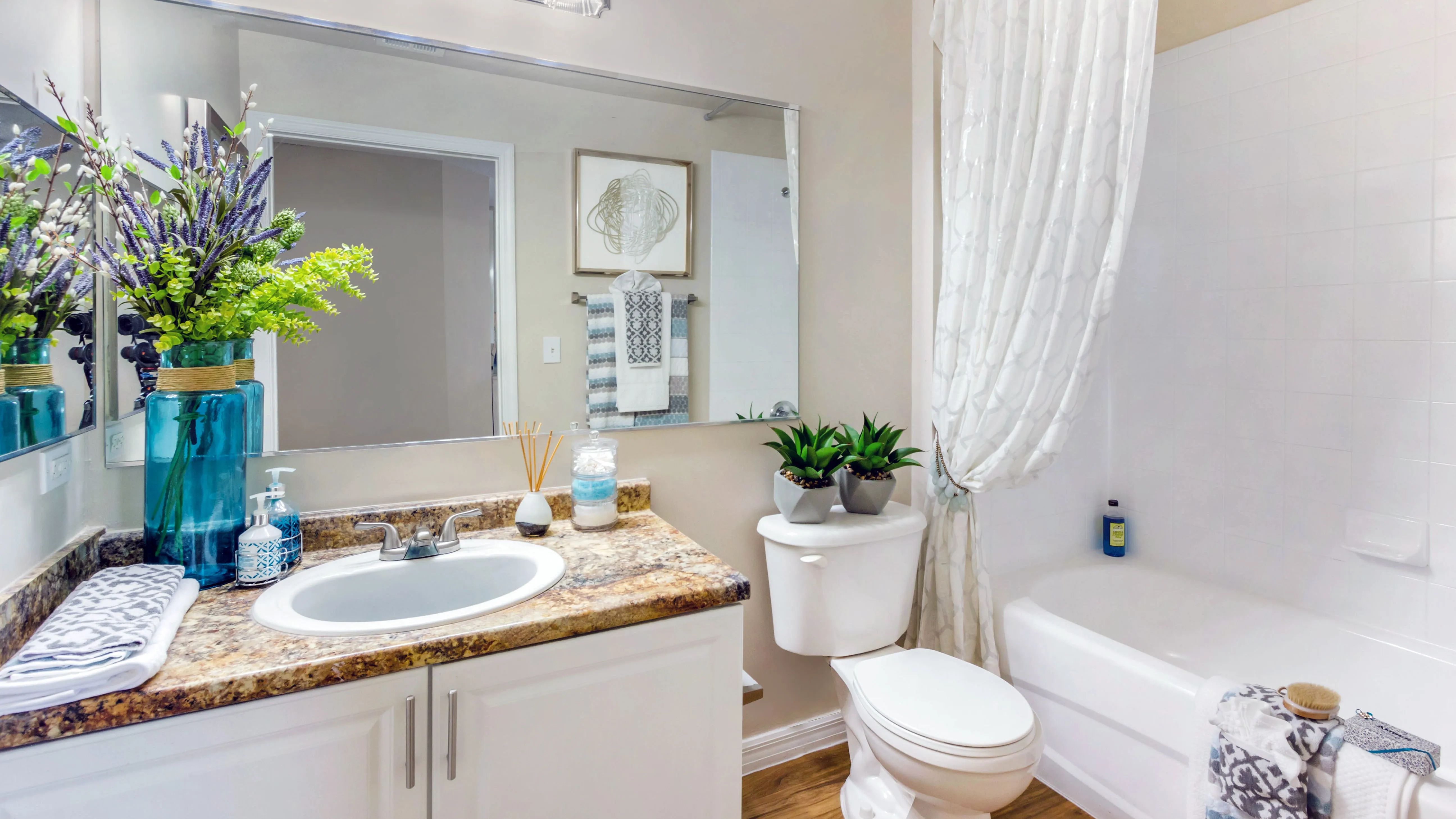 Elevate your daily routine in a bathroom that boasts rich Mascarella granite-style counters, large mirrors, and neutral tones.