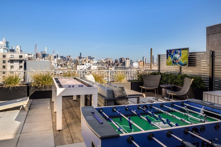 Rooftop terrace with lounge seating, foosball table, shuffleboard, and cornhole set