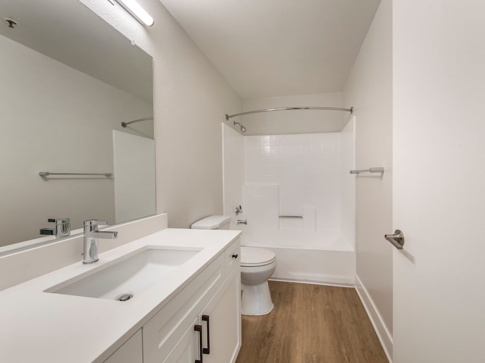 Renovated Package I bath with white quartz countertops, white cabinetry, and hard surface flooring