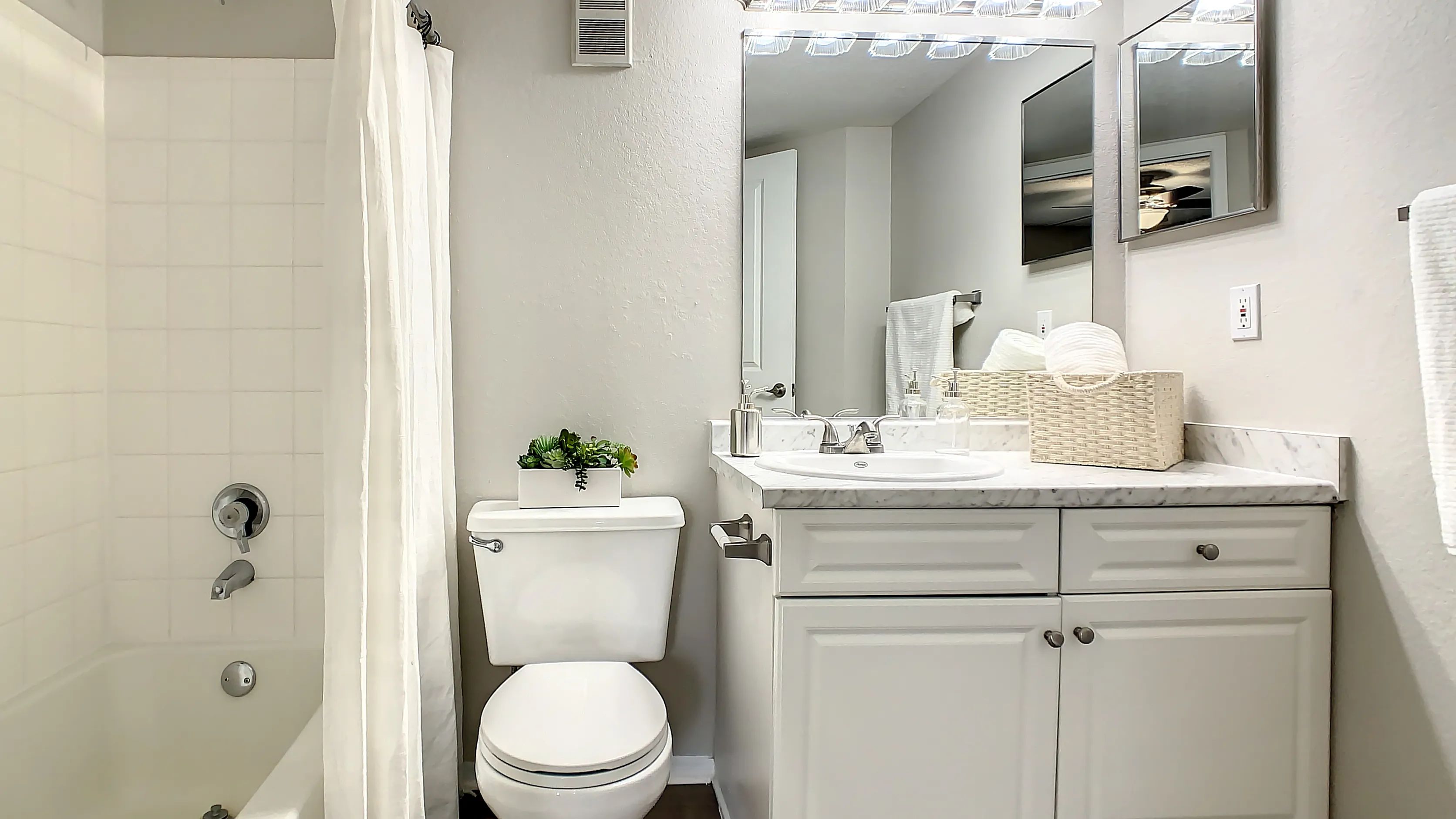 This bathroom features a full tub and shower combo and excellent vanity lighting.