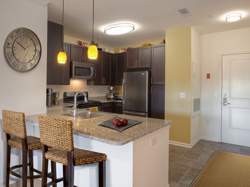 Classic Package kitchen with espresso cabinetry, beige speckled granite countertops, white tile backsplash, stainless steel appliances, and hard surface flooring