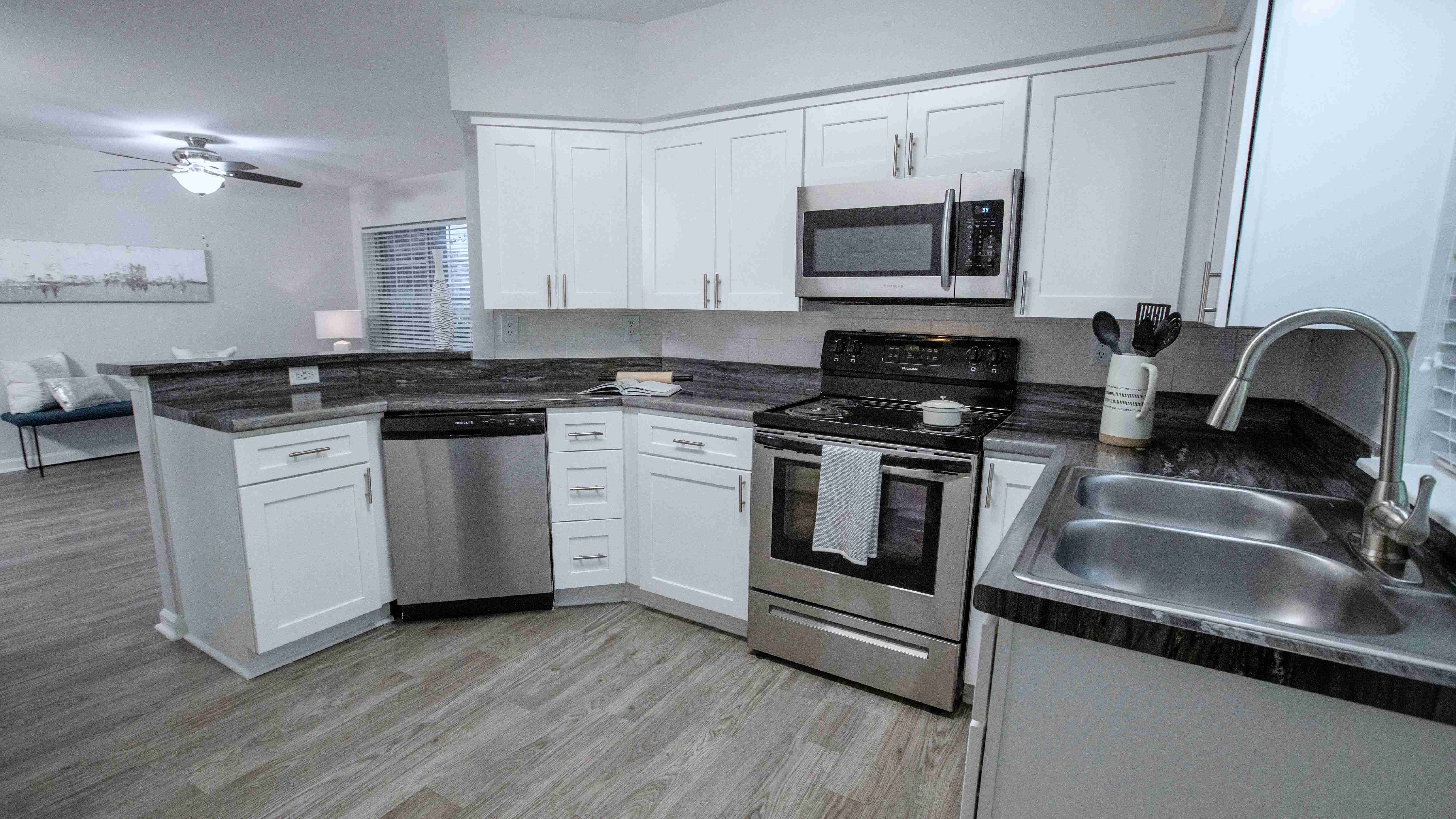 The black fusion countertops, white shaker cabinetry, and stainless-steel appliances add a touch of elegance to your kitchen, surrounded by ample cabinet space for all your culinary essentials.