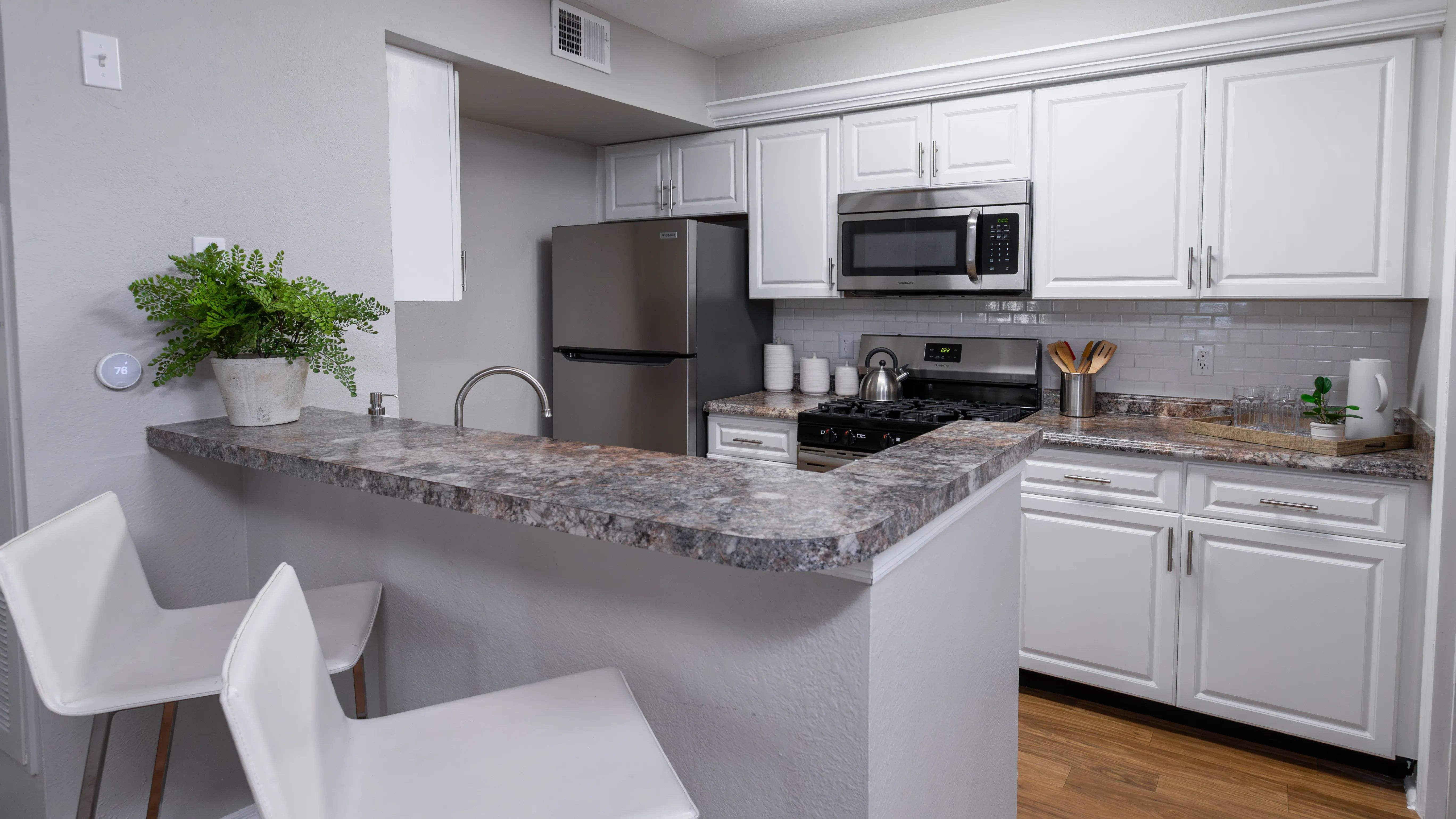 Whip up meals with ease in this stylish kitchen, complete with stainless steel appliances, white cabinetry, and a breakfast bar perfect for casual dining.
