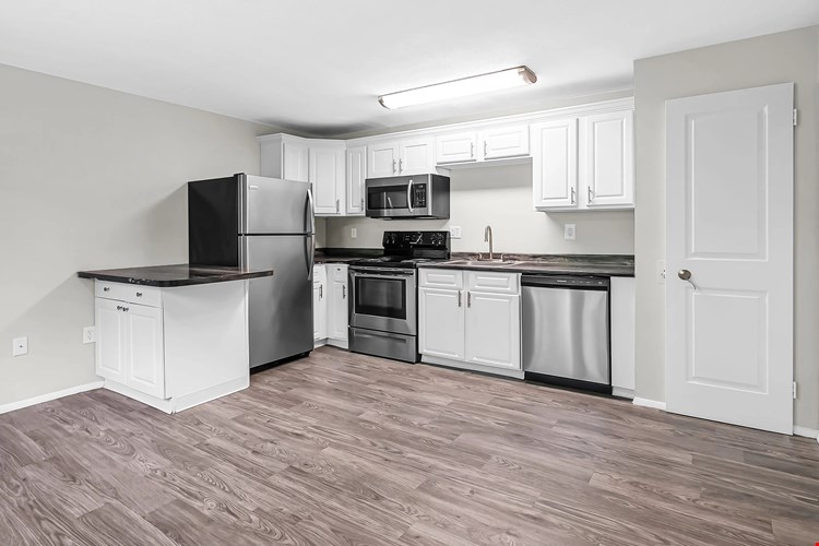 Experience harmonious living with an open-concept kitchen and living room both graced by stunning grey wood-style flooring.