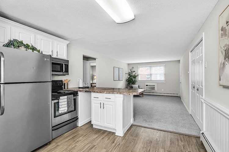 The kitchen layout in The Adler floor plan features wood-style flooring, stainless steel appliances, and a large breakfast bar.