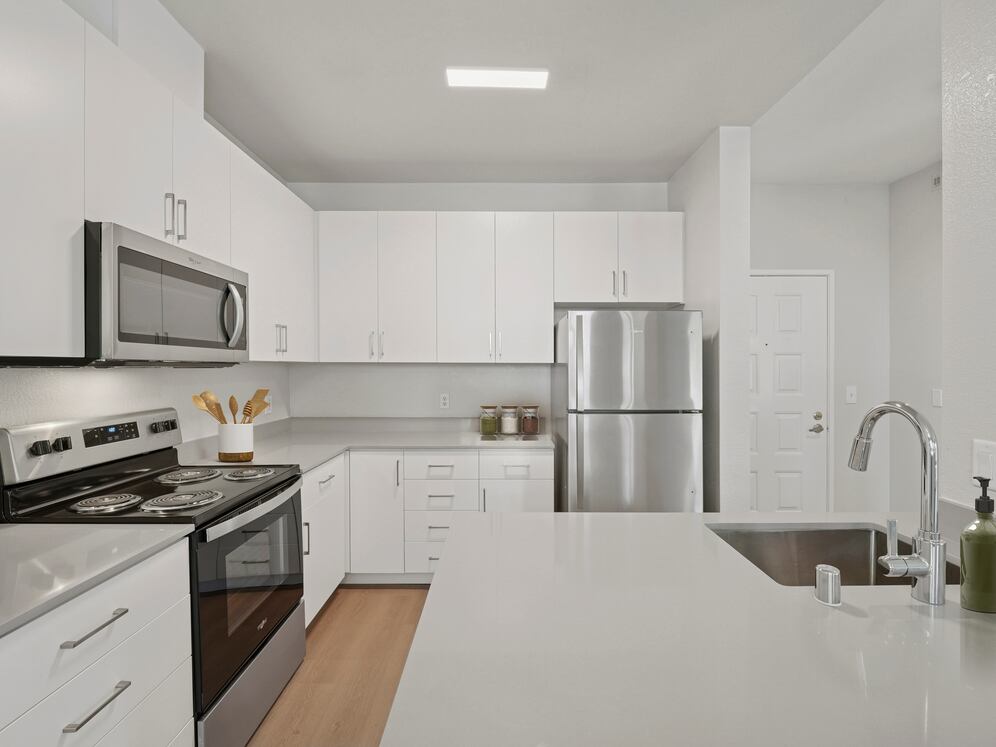 Renovated Package I kitchen with white cabinetry, grey quartz countertops, stainless steel appliances, and hard surface flooring