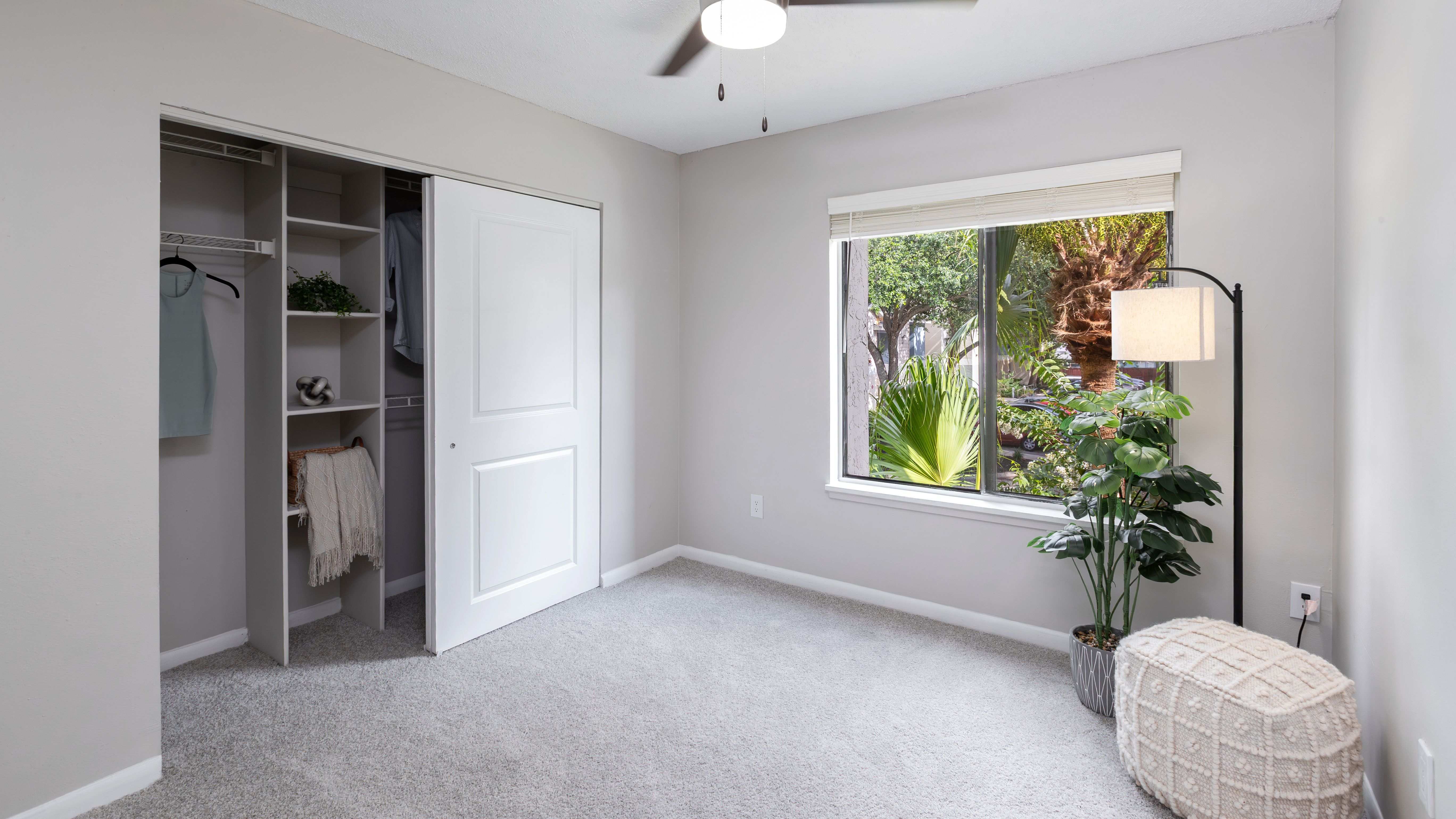 Bedrooms featuring plush carpeting, large windows, and a generous closet with built-in shelving for easy organization.