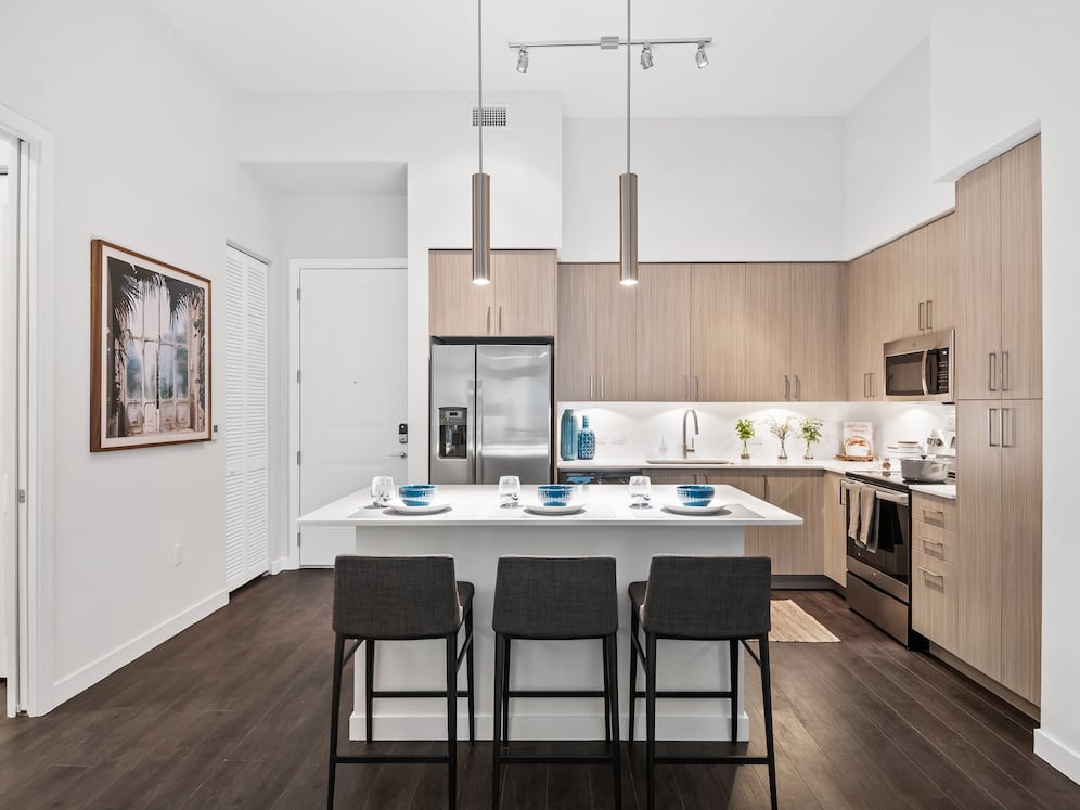 Kitchen with oak cabinetry, undercabinet lighting, white quartz countertops, and hard-surface vinyl plank flooring