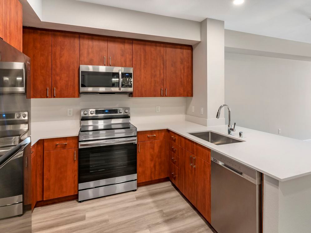 Renovated Package I kitchen with stainless steel appliances, white quartz countertops, cherry cabinetry, and hard surface flooring