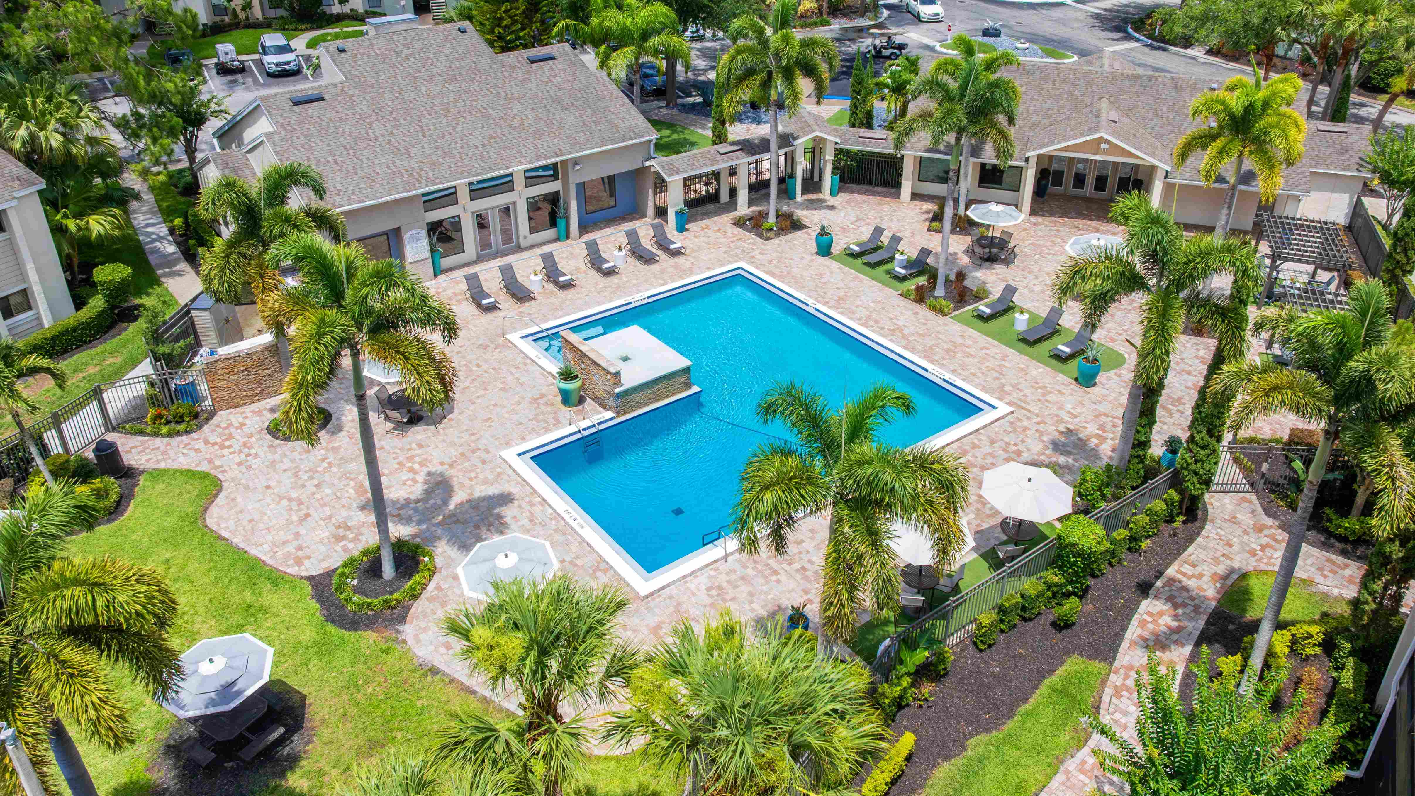 Enjoy the ultimate Florida lifestyle with our beautifully landscaped pool area featuring poolside loungers and umbrella-shaded seating areas.